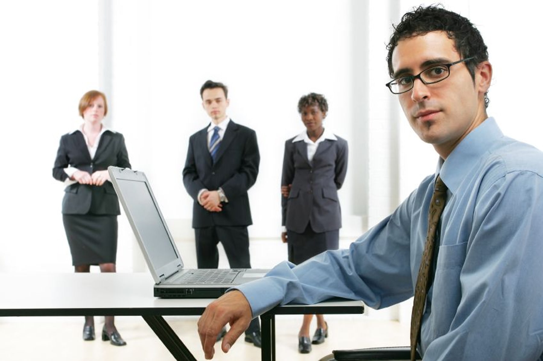 A my PC Techs consultant working on a laptop with a Phoenix business team behind him